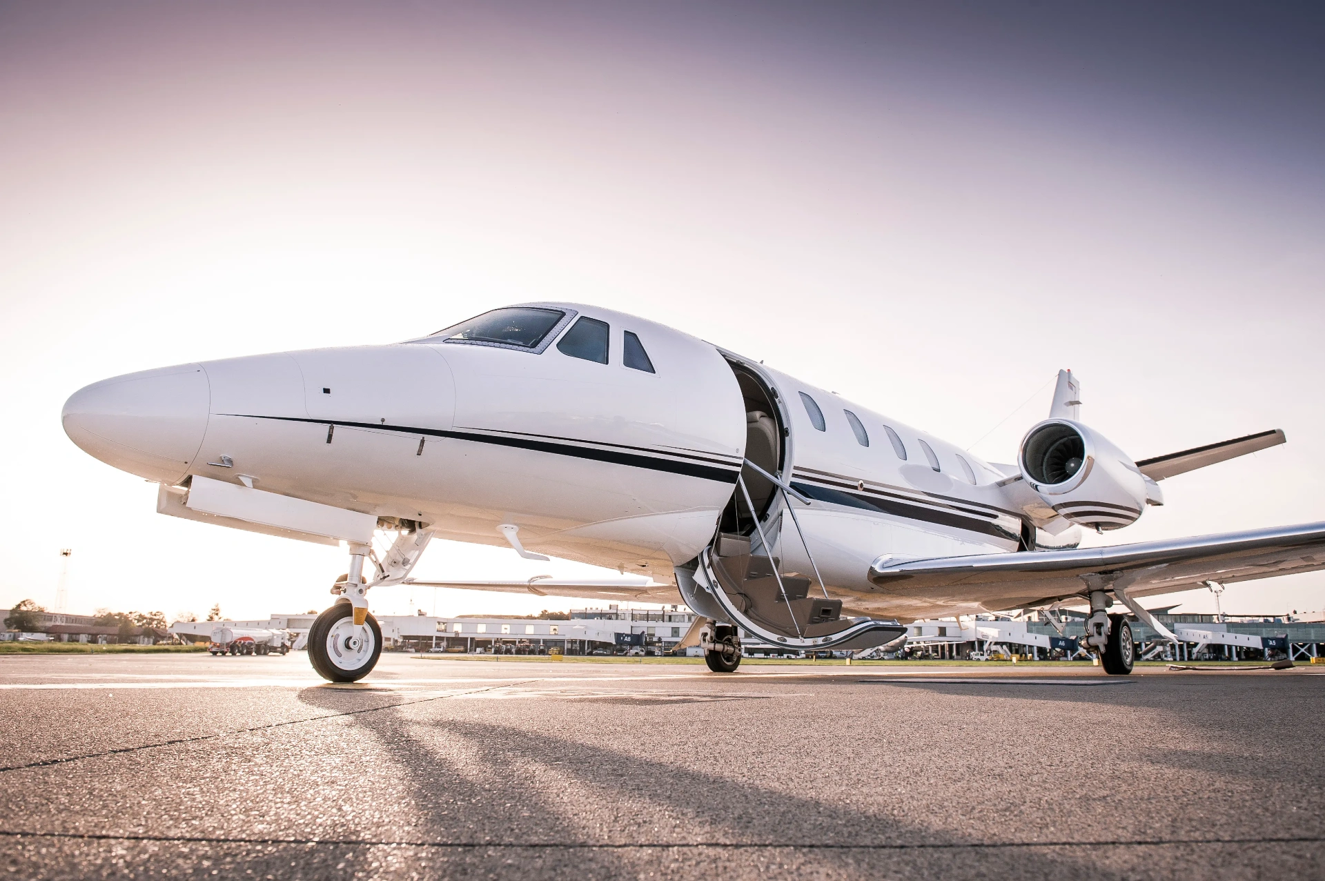Private jet on the tarmac at sunset with the cabin door open and airstairs deployed