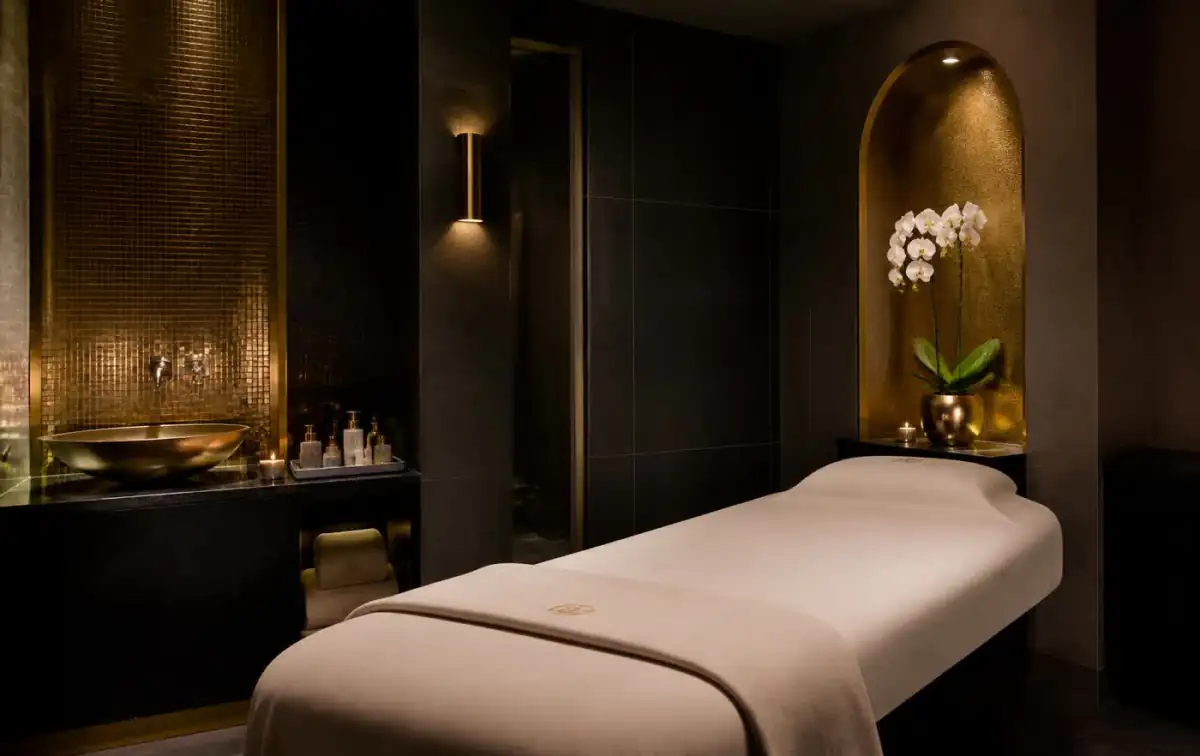 Candlelit spa treatment room with dark stone and gold detailing